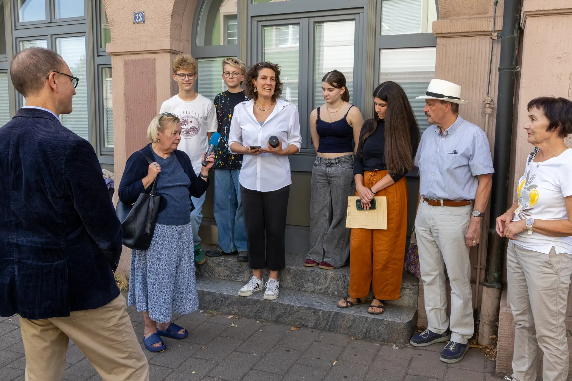 Nahaufnahme von zwei Stolpersteinen im Gehweg mit Metallplatten, im Hintergrund ein Straßenschild und weitere Details der Innenstadt.
