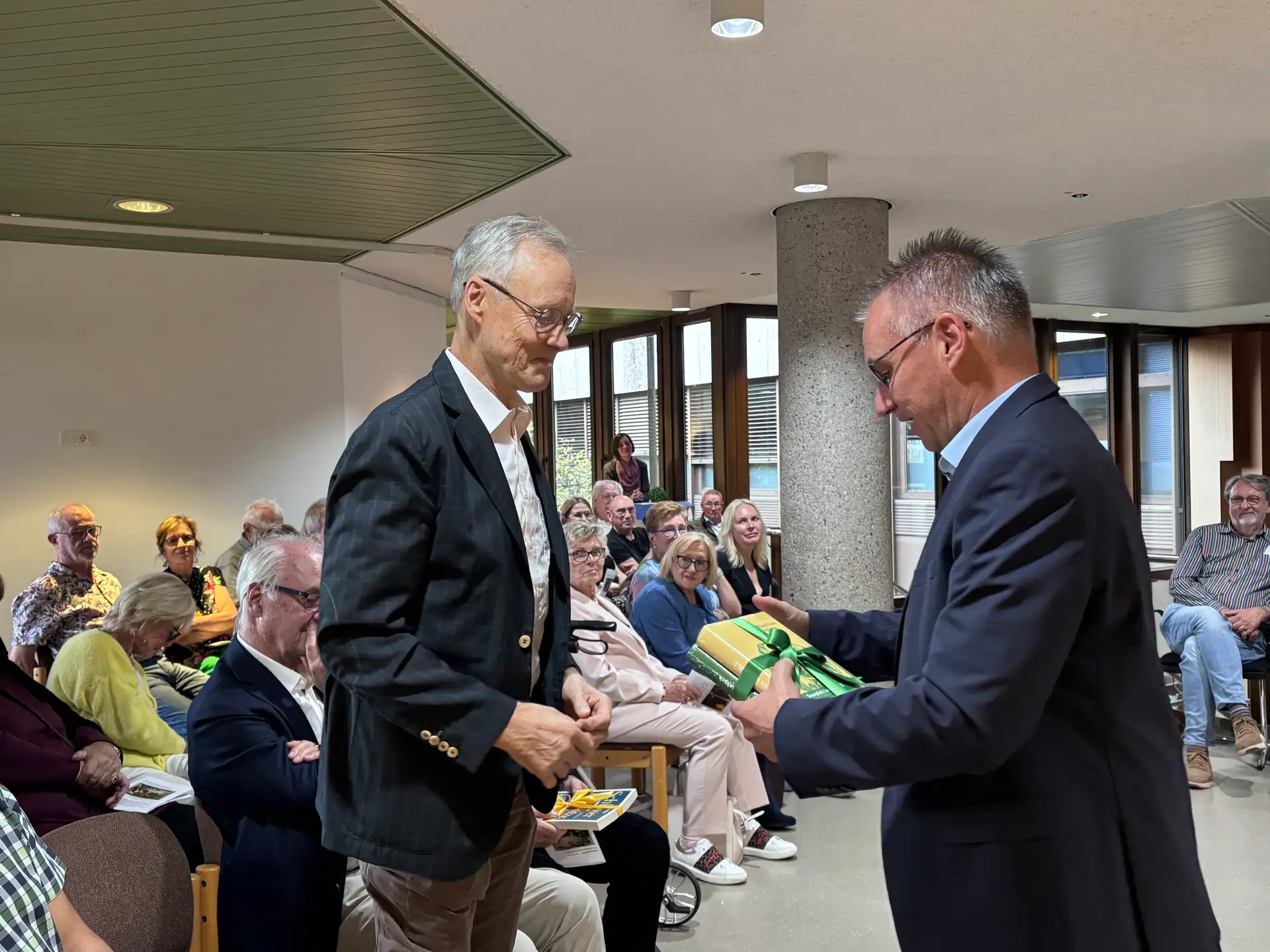 Personen stehen bei einer Ausstellungseröffnung im Forum; eine Person bedankt sich bei Prof. Dr. Max Lindemann.