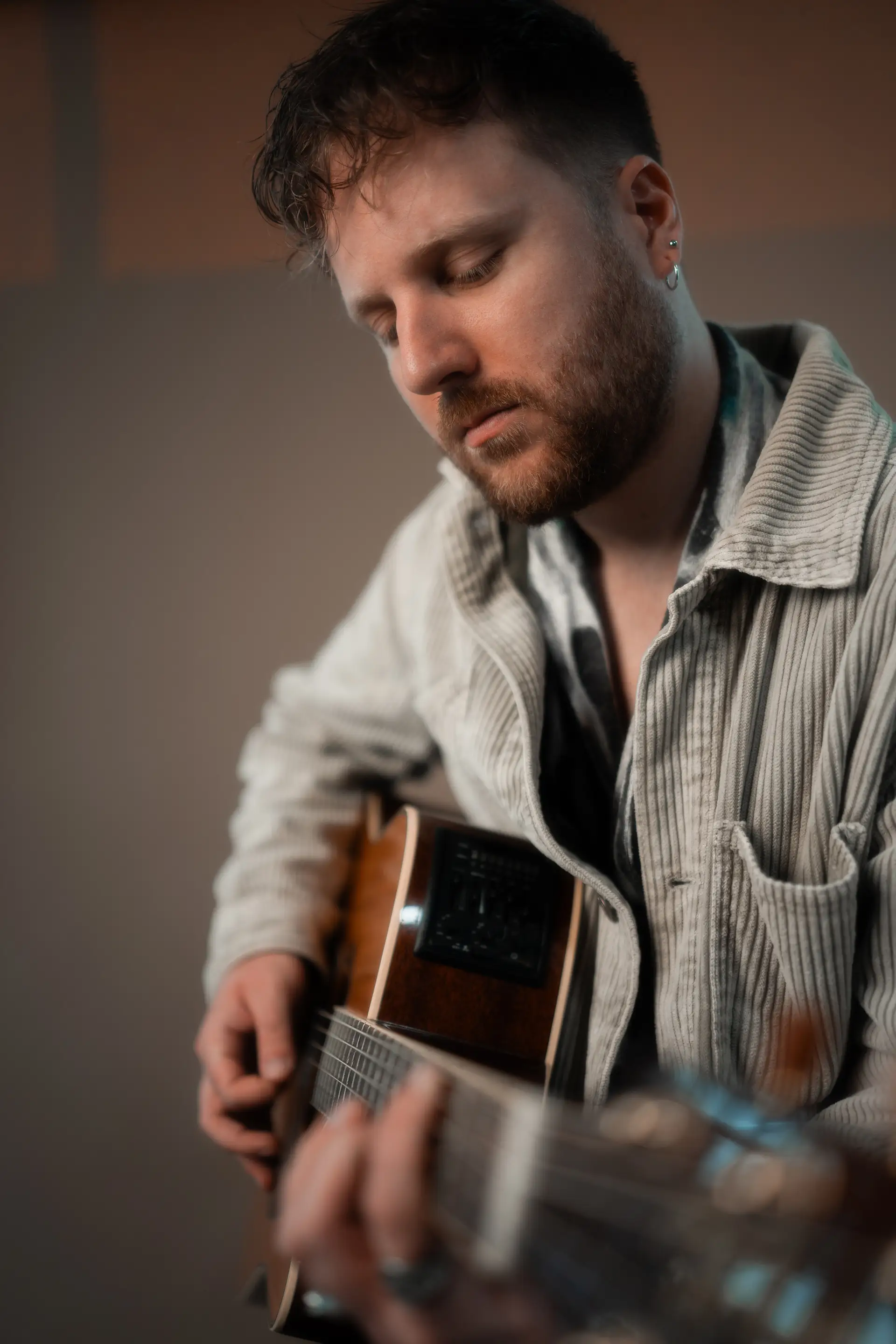 Philipp Leon spielt Akustikgitarre und blickt dabei nach unten.